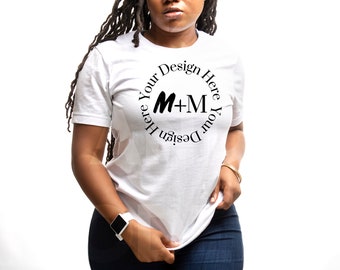 May include: White t-shirt with a black circle design that says "Design Your Here Your Design Here" with the letters M+M in the center.