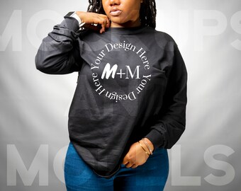 Op de afbeelding: Een zwart longsleeve shirt met de tekst "Design Your Here Your Design Here" in een cirkel rond de tekst "M+M".