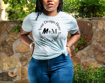May include: A light blue t-shirt with a black circle design that says "Design Your Here M+M Your Design Here".