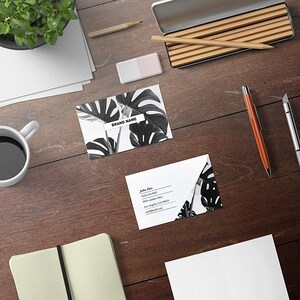 May include: Two business cards with a black and white tropical leaf design. The top card has the text "BRAND NAME" on it. The bottom card has the text "John Doe" and contact information.