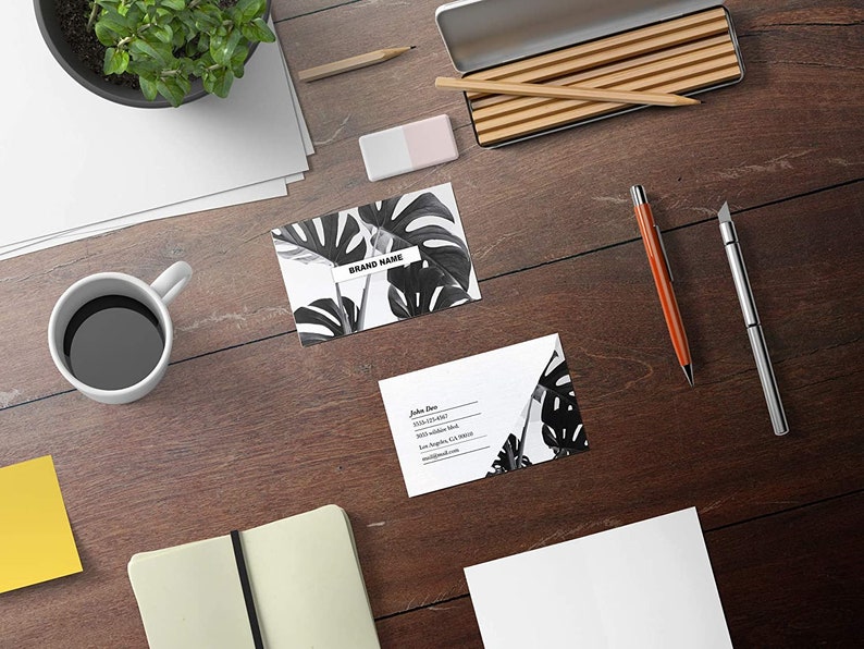 May include: Two business cards with a black and white tropical leaf design. The top card has the text "BRAND NAME" on it. The bottom card has the text "John Doe" and contact information.