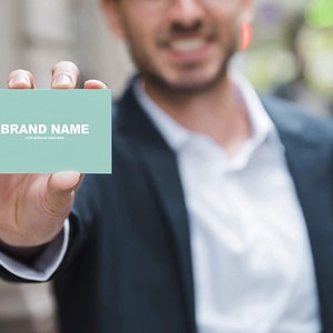 May include: A person holding a light blue business card with the text "BRAND NAME" and the words "YOUR MESSAGE GOES HERE".