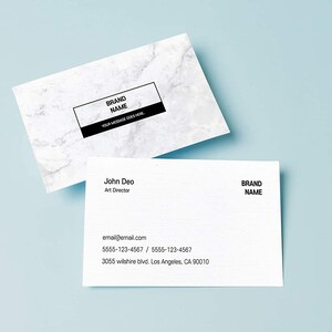 May include: White business card with black text. The text reads "BRAND NAME" and "YOUR MESSAGE GOES HERE". A second white business card with black text reads "John Deo, Art Director, email@email.com, 5555-123-4567 / 5555-123-4567, 3055 Wilshire Blvd. Los Angeles, CA 90010, BRAND NAME".