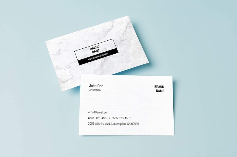 May include: White business card with black text. The text reads "BRAND NAME" and "YOUR MESSAGE GOES HERE". A second white business card with black text reads "John Deo, Art Director, email@email.com, 5555-123-4567 / 5555-123-4567, 3055 Wilshire Blvd. Los Angeles, CA 90010, BRAND NAME".