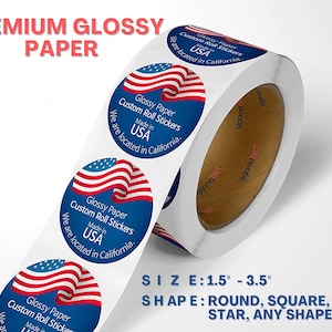 May include: Roll of glossy paper stickers with an American flag design. The stickers are round and feature the text "Glossy Paper Custom Roll Stickers Made in USA We are located in California." The roll is white with a brown core and the text "SIZE: 1.5" - 3.5" SHAPE: ROUND, SQUARE, HEART, STAR, ANY SHAPE"
