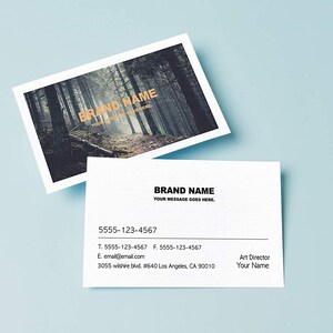 May include: A white business card with black text. The text reads "BRAND NAME" followed by "YOUR MESSAGE GOES HERE". Below the text is a phone number, email address, and physical address. The card is on a light blue background.