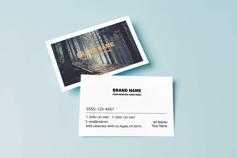 May include: A white business card with black text. The text reads "BRAND NAME" followed by "YOUR MESSAGE GOES HERE". Below the text is a phone number, email address, and physical address. The card is on a light blue background.