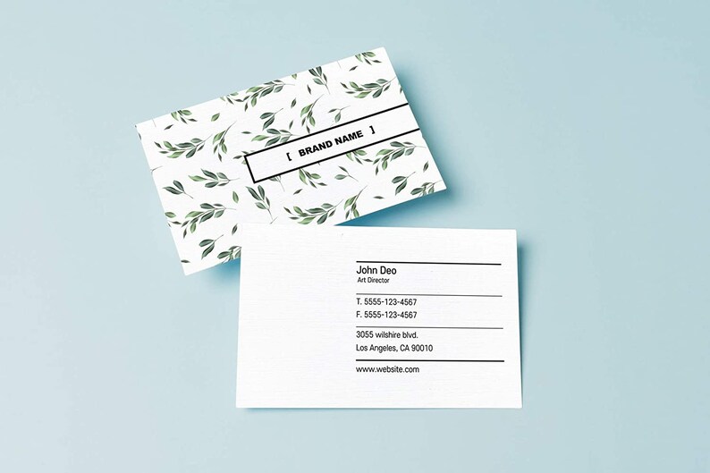 May include: A white business card with a green leafy pattern and the text "[BRAND NAME]" on the top. The bottom of the card has the name "John Deo", the title "Art Director", a phone number, a fax number, an address, and a website address.