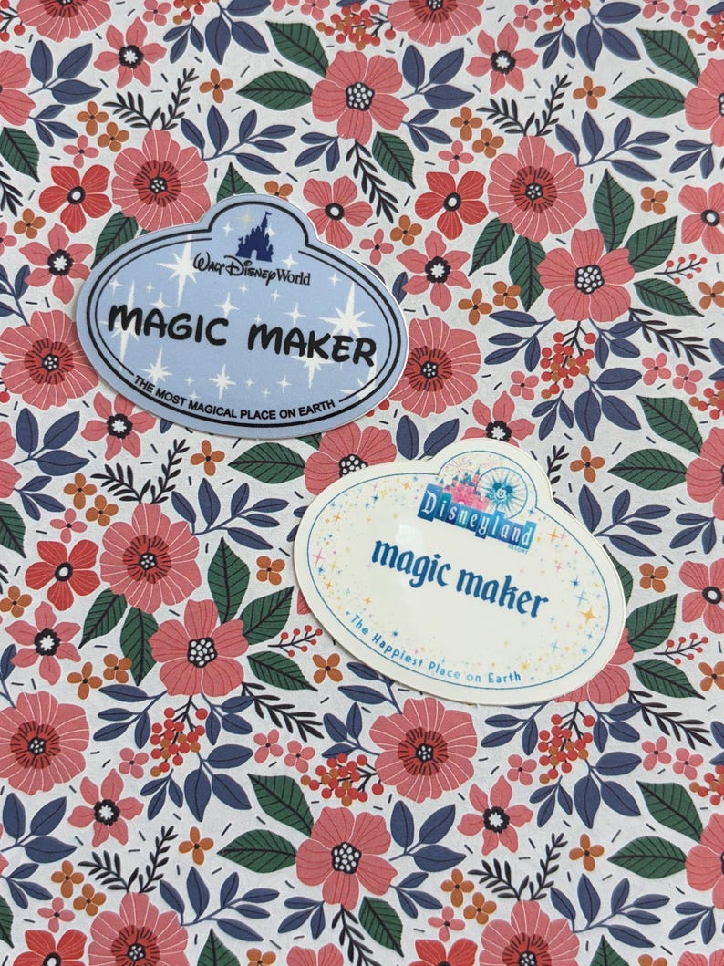 May include: Two oval-shaped name tag stickers featuring floral patterns. One light blue sticker reads Walt Disney World MAGIC MAKER THE MOST MAGICAL PLACE ON EARTH. The other white sticker reads Disneyland magic maker The Happiest Place on Earth.