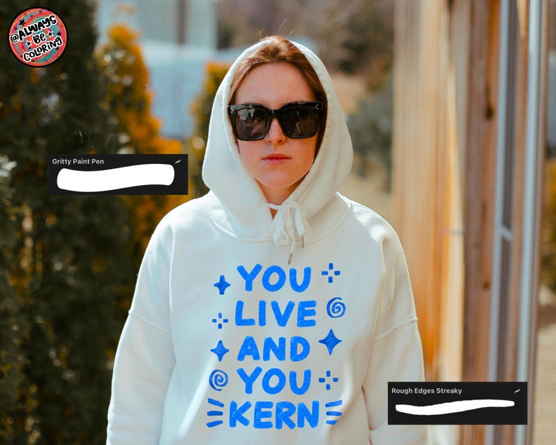 May include: A person wearing a white hooded sweatshirt with the text "YOU LIVE AND YOU KERN" in blue. The person is also wearing black sunglasses. The image has a warm, natural light.