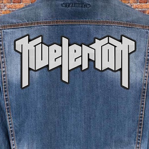 Peut inclure: Une veste en jean avec un patch brodé blanc qui dit "Tuelertot" au dos.