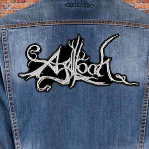 Op de afbeelding: Een zwart denim jack met een wit geborduurd patch met de tekst "Abloom" op de rug.