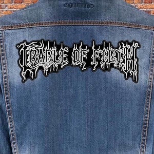 May include: A black denim jacket with a white embroidered patch that says "CRADLE OF FILTH" on the back.