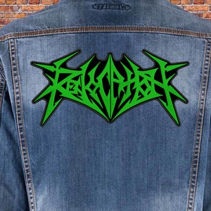 Peut inclure: Patch brodé vert et noir avec le mot "REVOCATION" dans une police de caractères stylisée. Le patch est cousu sur une veste en jean bleue.