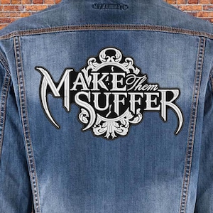 May include: A black and white embroidered patch with the text "MAKE THEM SUFFER" in a gothic font. The patch is surrounded by a decorative floral design.