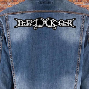 Könnte beinhalten: Eine blaue Jeansjacke mit einem schwarzen und weißen gestickten Aufnäher, auf dem "BELAKOR" steht, auf der Rückseite.