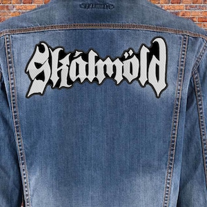 May include: A denim jacket with a white embroidered patch that says "Skalmold" on the back.