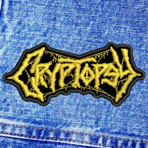 Peut inclure: Un écusson brodé noir et or avec le mot "KRYPTOS" dans une police gothique.