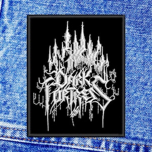 May include: Black and white embroidered patch featuring the text "Dark Fortress" in a gothic font. The text is surrounded by a design of a castle with towers.