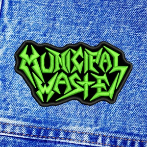 Puede incluir: Parche bordado verde con el texto "MUNICIPAL WASTE" sobre un fondo negro. El parche está cosido en una chaqueta vaquera azul.
