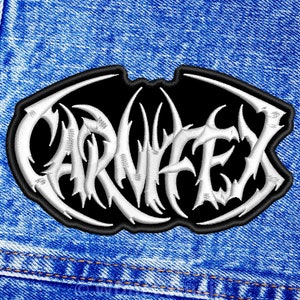 May include: A black and white embroidered patch with the word "CARNIFEX" in a stylized font. The patch is on a blue denim background.