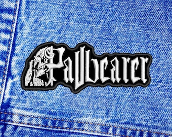 May include: Black and white embroidered patch with the word "Pallbearer" in white lettering on a black background. A skull with a cross bone is on the left side of the patch.