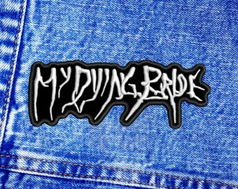 May include: Embroidered patch featuring the words "MY DYING BRIDE" in white, distinctive lettering on a black base. The patch has a black border and is displayed on a blue denim fabric background.