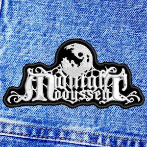 Op de afbeelding: Een geborduurde patch in zwart en wit met de tekst "Midnight Odyssey" en een wit maanontwerp.
