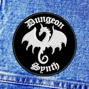 以下が含まれることがあります： 白いドラゴンとゴシック体で「Dungeon Synth」という文字が書かれた黒と白の刺繍パッチ