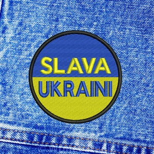 May include: A blue and yellow embroidered patch with the text "SLAVA UKRAINI" on a denim background.