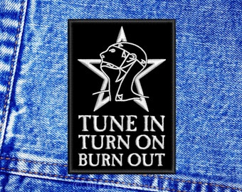 May include: Black and white embroidered patch featuring a star and a stylised human head. The text "TUNE IN TURN ON BURN OUT" is below the star.