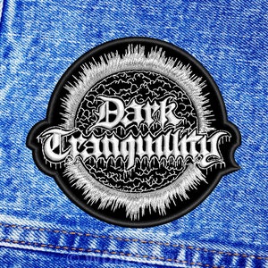 Op de afbeelding: Zwart-witte geborduurde patch met de tekst "Dark Tranquility" in een gestileerd lettertype. De patch is omgeven door een wit zonnestralenontwerp.