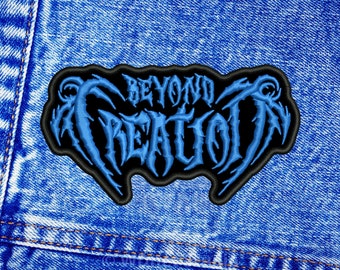 May include: Embroidered patch featuring the text "BEYOND CREATION" in a blue, gothic-style font. The patch has a black border and is displayed on a blue denim fabric. The design has a heavy metal aesthetic.