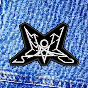 Może przedstawiać: Naszywkę haftowaną w kolorze czarnym i białym z wzorem pentagramu. Naszywka jest przyszyta do niebieskiej dżinsowej kurtki.
