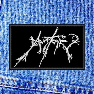 May include: Black embroidered patch with the word "Aether" in white lettering on a denim background.