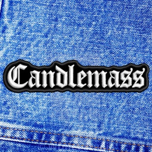 Op de afbeelding: Een geborduurde patch in zwart en wit met het woord "Candlemass" in een gotisch lettertype.