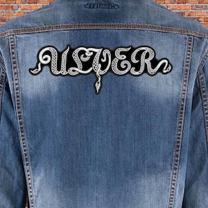 Può includere: Una giacca di jeans con una toppa ricamata bianca che dice "ALVER" in un design a forma di serpente.