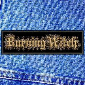 May include: A black rectangular patch featuring the words "Burning Witch" in gold-coloured, ornate lettering. The patch is set against a blue denim background, with visible stitching.
