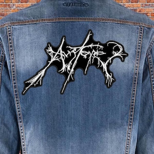 May include: A black denim jacket with a white embroidered patch that says "Aether" on the back.