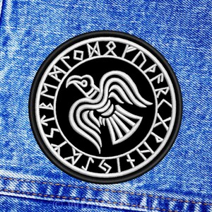 Könnte beinhalten: Eine weiße Keramik-Tasse mit schwarzem Henkel und dem Text "But First, Coffee" in fetter, schwarzer Schrift. Die Tasse steht vor einem verschwommenen Hintergrund, der eine gemütliche Umgebung andeutet.