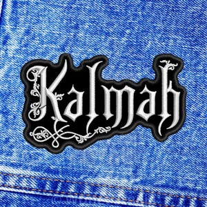 May include: A black embroidered patch featuring the white text Kalmah in a stylized gothic font with intricate scrollwork details, centered on a blue denim fabric background with visible stitching along the left side of the material.