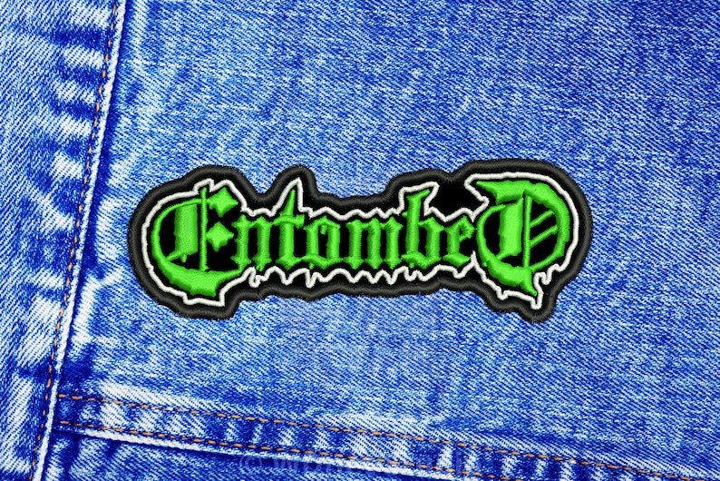 K&ouml;nnte beinhalten: Gr&uuml;n-schwarzer gestickter Aufn&auml;her mit dem Wort "Entombed" in gotischer Schrift.
