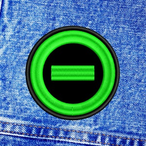 May include: A black and green embroidered patch with a circle and a horizontal line inside. The circle is outlined in black and the line is green.