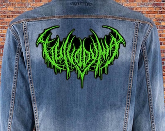 May include: Green embroidered patch with the word "EVIL" in a gothic font on a black background. The patch is attached to a blue denim jacket.
