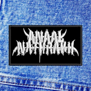 May include: A black patch with white embroidered text that reads "ANAL NATHRAKH".