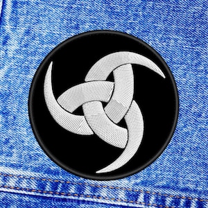 May include: A black and white embroidered patch with a white triple horned symbol on a black background.