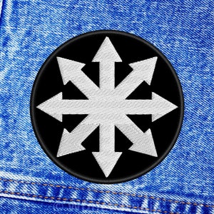 Pode incluir: Um remendo bordado em preto e branco com uma estrela branca de oito pontas com flechas apontando para fora. O remendo está sobre um fundo de denim azul.