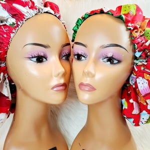 May include: Two red satin Christmas-themed shower caps. One cap features a Santa Claus design, the other features a gingerbread cookie design.