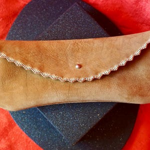 May include: A tan leather clutch bag with a scalloped edge and a silver button closure.