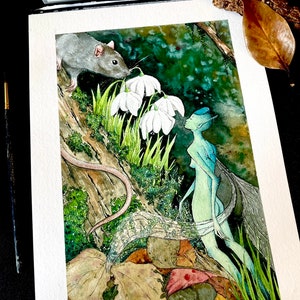 May include: Watercolor painting of a fantasy scene featuring a gray rat, a fairy, and white flowers. The fairy has blue skin and wings. The artwork is on white paper, with a palette of watercolors and a paintbrush visible.